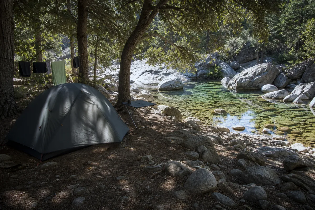 Tente montée sur un emplacement ombragé d’un camping corse en bord de rivière