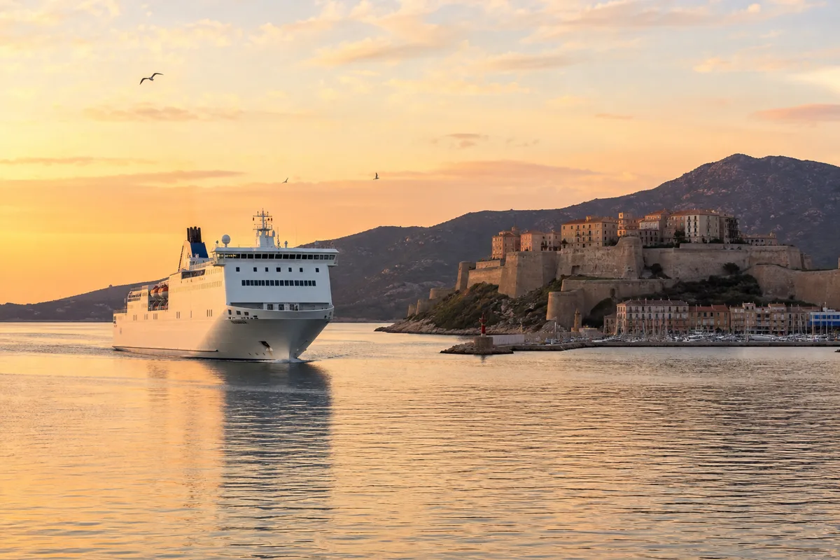 Ferry approchant un port corse au lever du soleil