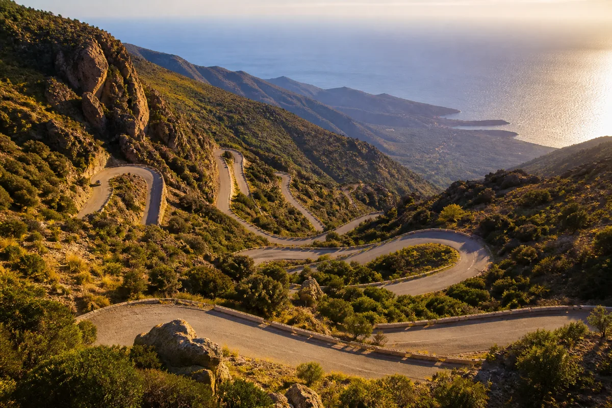 Route de montagne corse en lacets surplombant la mer, en fin d&rsquo;après-midi