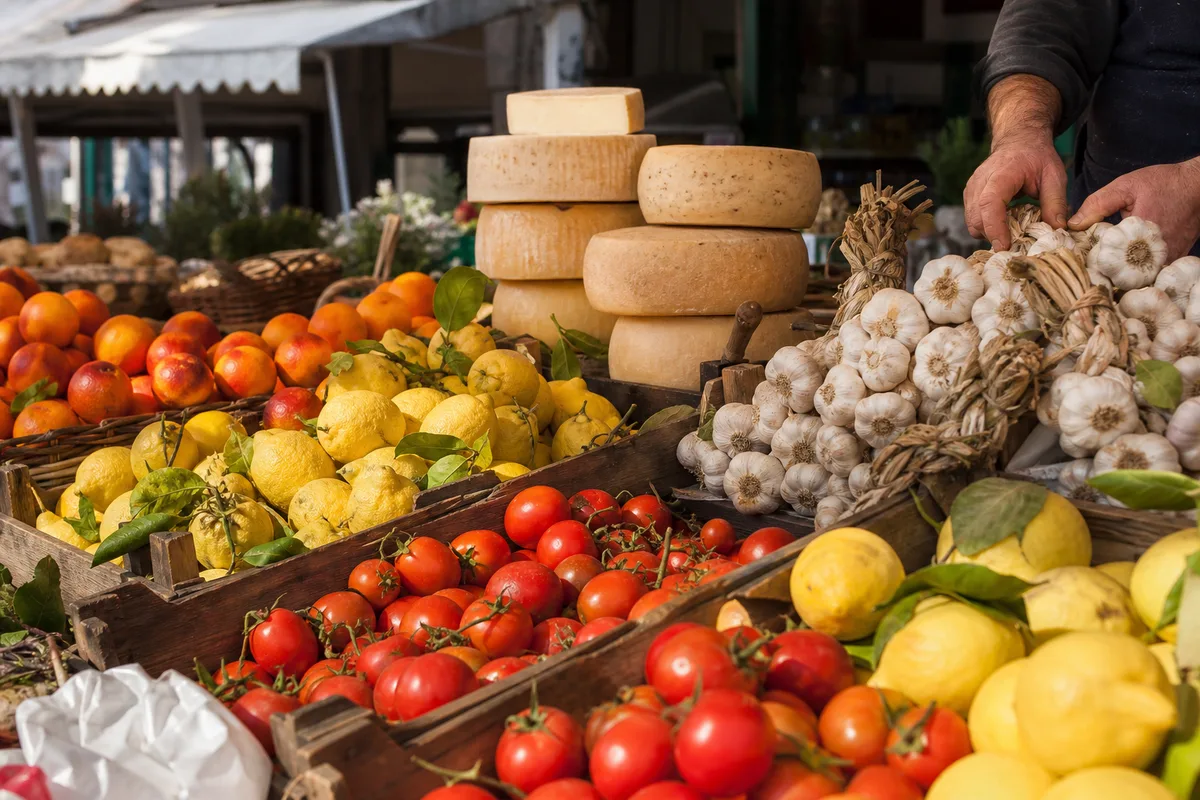 Étal de marché italien avec tomates, agrumes et fromages régionaux